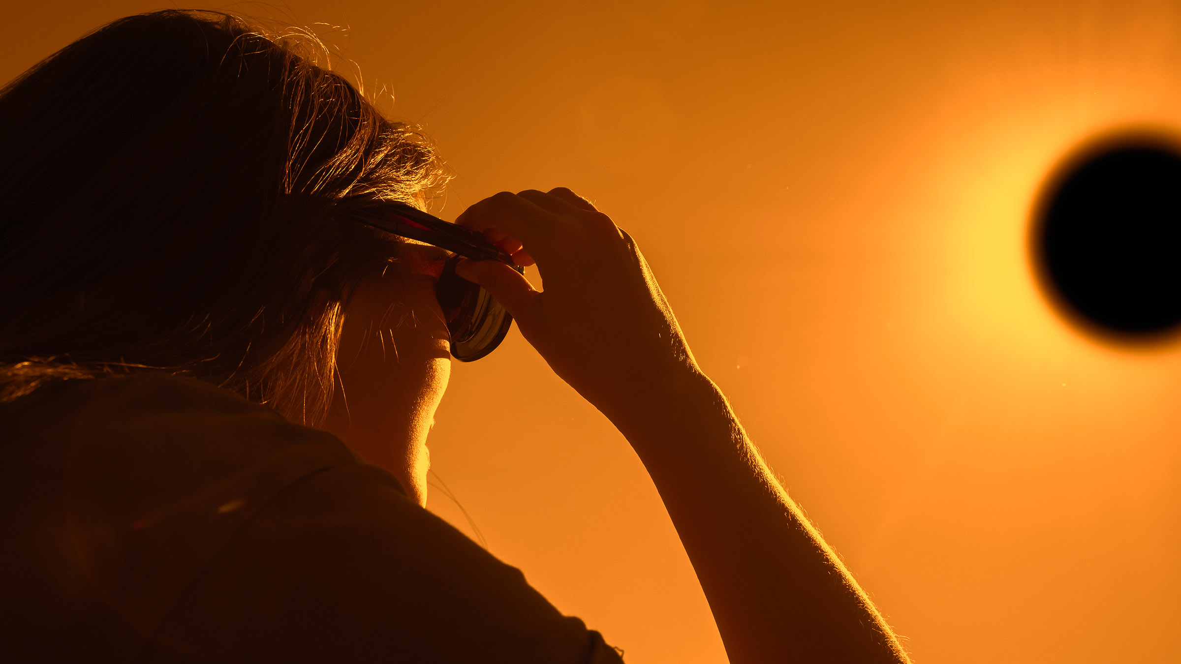 Woman is looking on solar eclipse through three sunglasses. Sun eclipse concept.