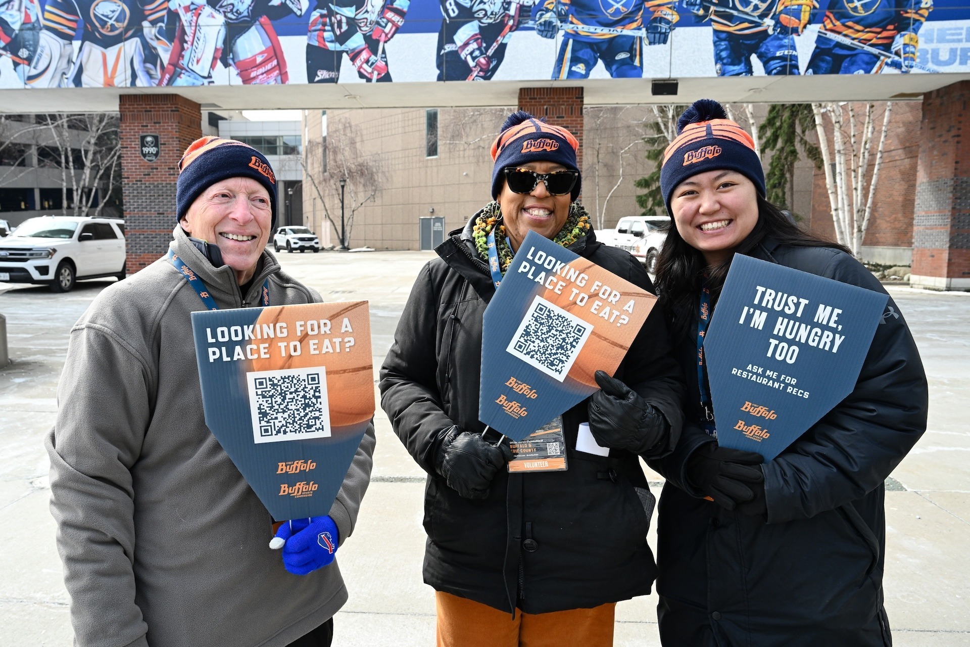 visit buffalo sports commission volunteers smiling with food recommendation signs