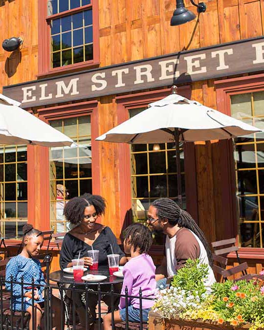 A family sits outside and laughs while eating food at Elm Street Bakery in East Aurora.